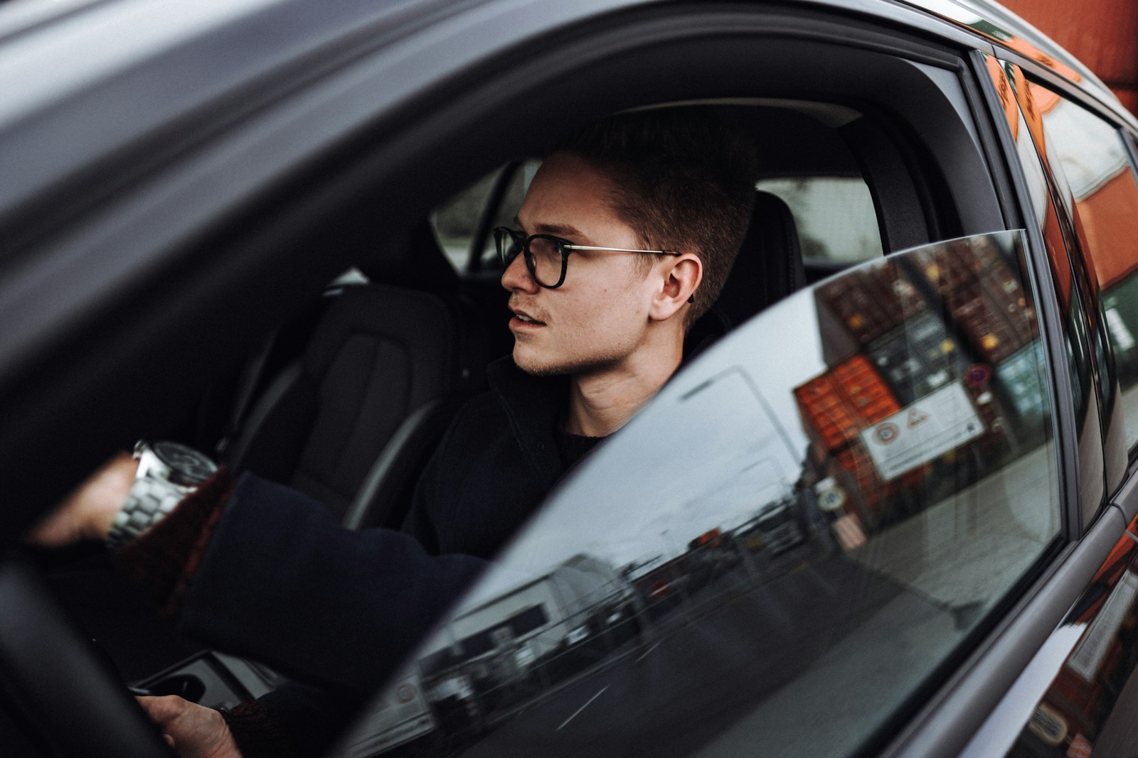 man in black jacket wearing eyeglasses sitting inside car, auto