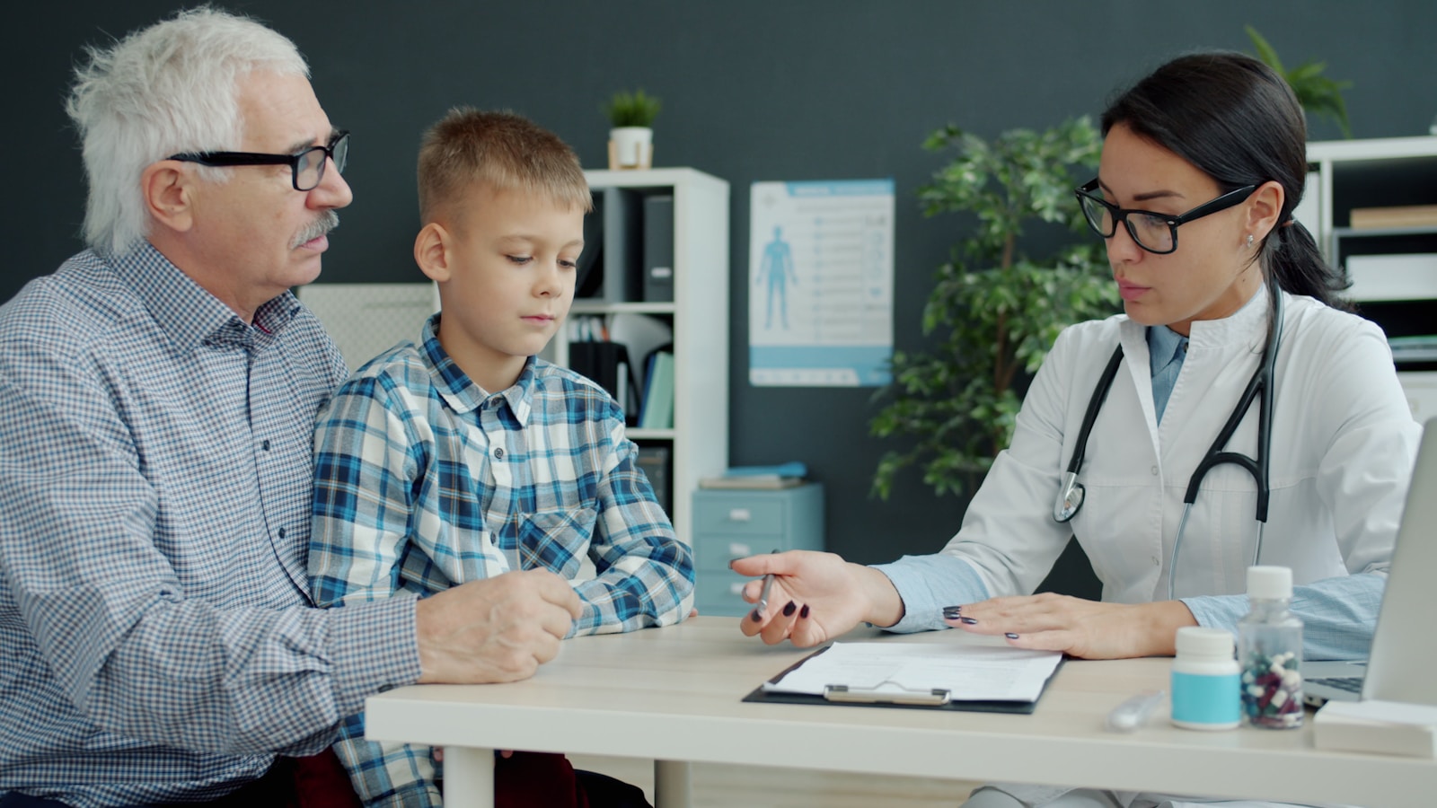 Doctor consults with grandfather and grandson in office, heath