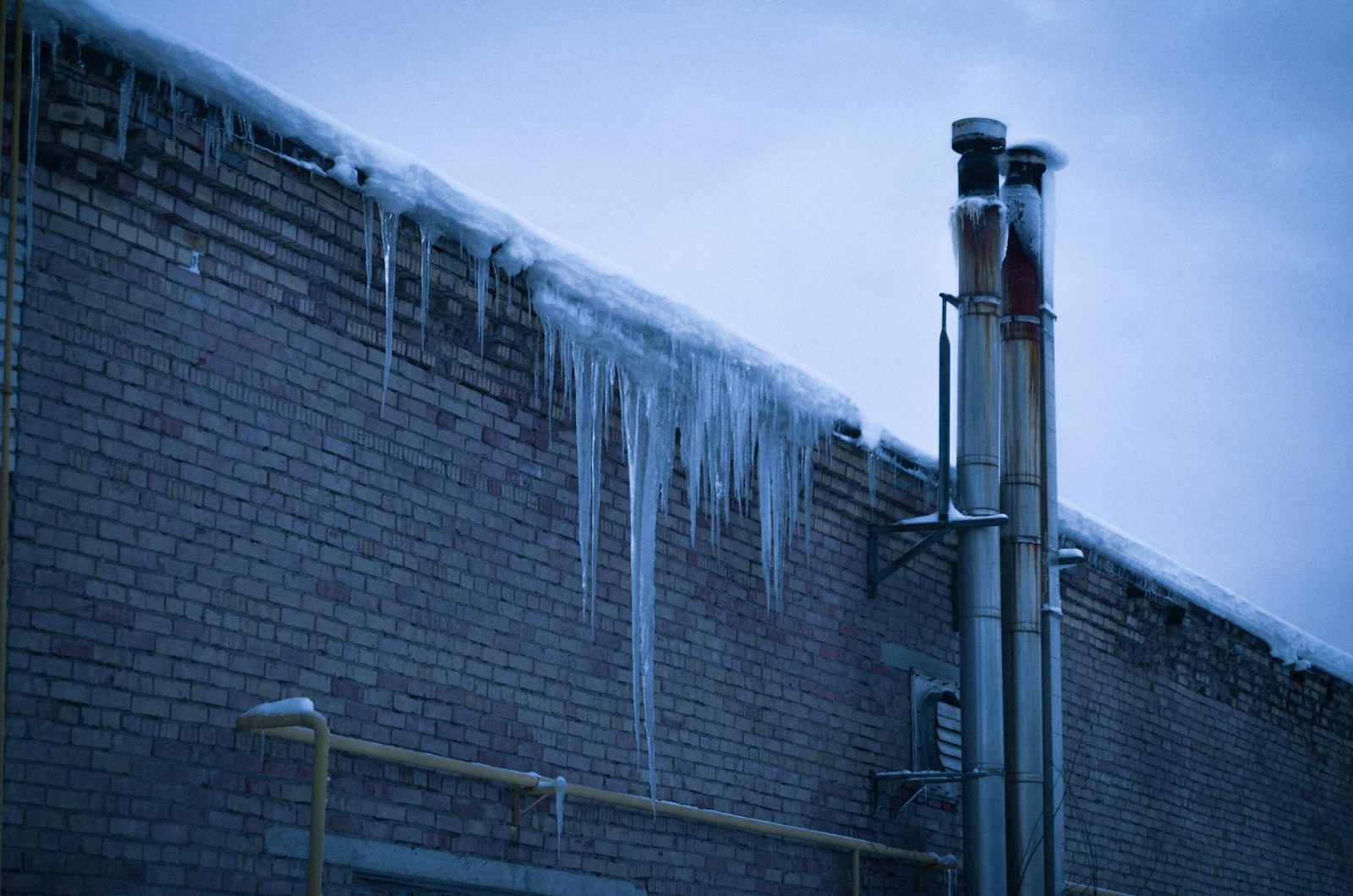 gray metal pipe on brown brick wall
